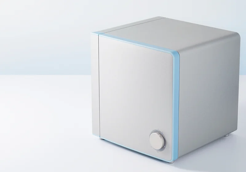 青いアクセントラインと丸いつまみが付いた、キューブ型の灰色の家電製品